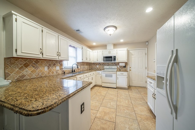 4021 Shade Valley Dr, Columbus, GA 31909 - kitchen featuring white appliances, a peninsula, recessed lighting, tasteful backsplash, and dark stone counters