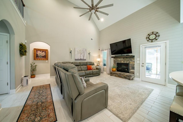 82 Rolling Meadows Way, Waverly Hall, GA 31831 - living area with high vaulted ceiling, arched walkways, a ceiling fan, a stone fireplace, and light wood-style flooring