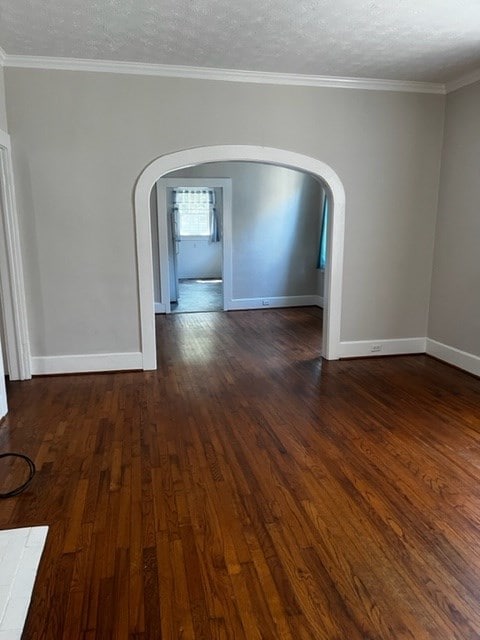 unfurnished room featuring crown molding, dark wood-type flooring, and a textured ceiling