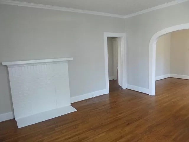 unfurnished living room featuring crown molding and dark hardwood / wood-style floors