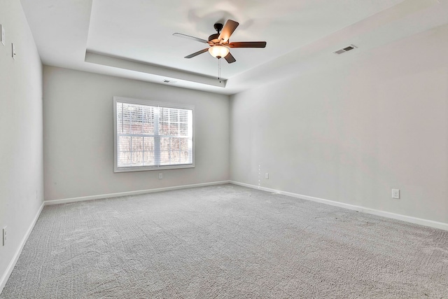 spare room with carpet flooring, a raised ceiling, and ceiling fan