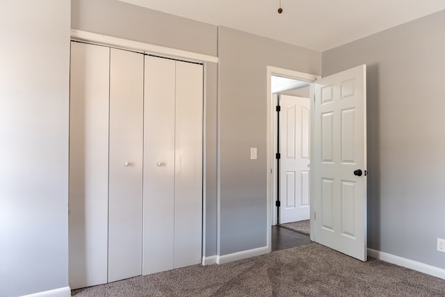 unfurnished bedroom with carpet, a closet, and baseboards