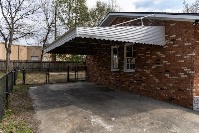 view of parking / parking lot with a carport, driveway, fence, and a gate