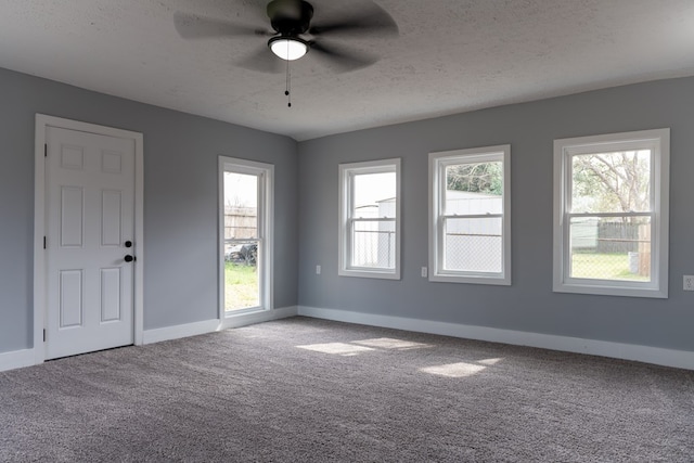 carpeted spare room with a textured ceiling, ceiling fan, plenty of natural light, and baseboards