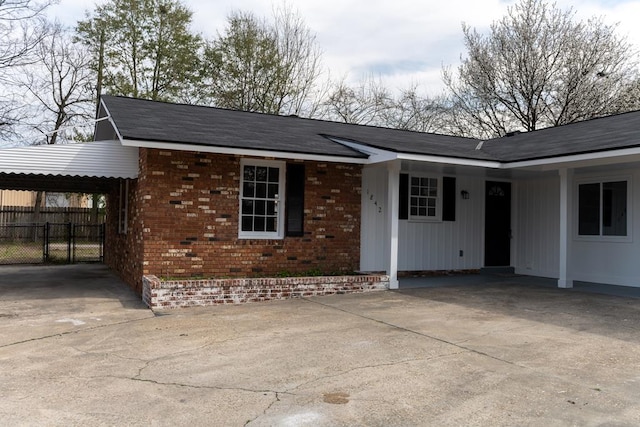 single story home featuring a carport, fence, concrete driveway, and brick siding