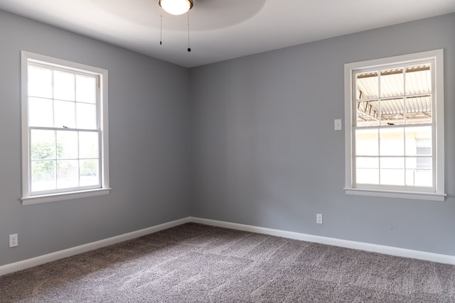 carpeted spare room featuring ceiling fan and baseboards