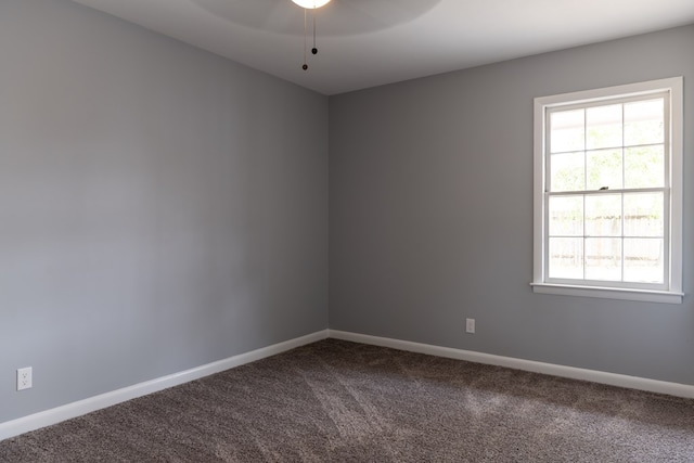 unfurnished room with baseboards, dark carpet, and a ceiling fan