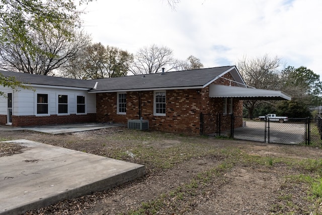 view of front of house featuring a gate, fence, central AC, and brick siding