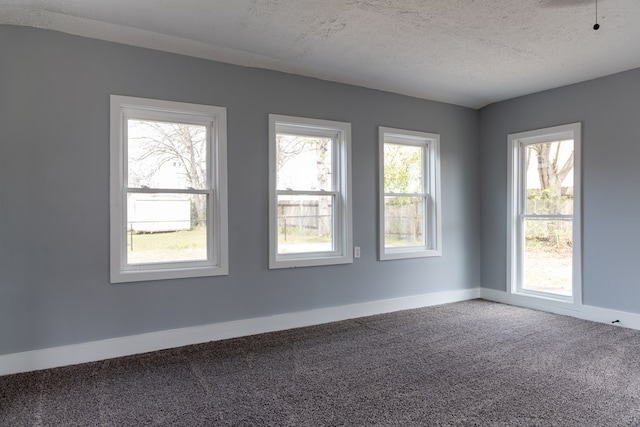 empty room featuring a textured ceiling, carpet floors, and baseboards