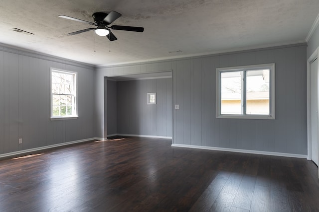 unfurnished room featuring dark wood-style floors, visible vents, ornamental molding, and baseboards