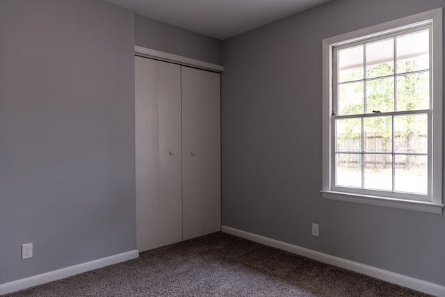 unfurnished bedroom with carpet, a closet, multiple windows, and baseboards