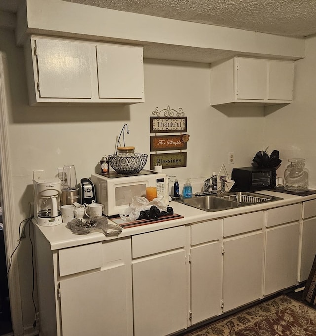 909 16th Ave, Phenix City, AL 36867 - kitchen featuring white microwave, a sink, white cabinetry, light countertops, and a textured ceiling