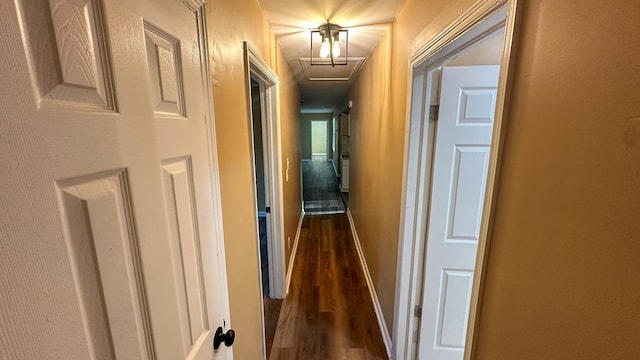 corridor with dark wood-style flooring and baseboards