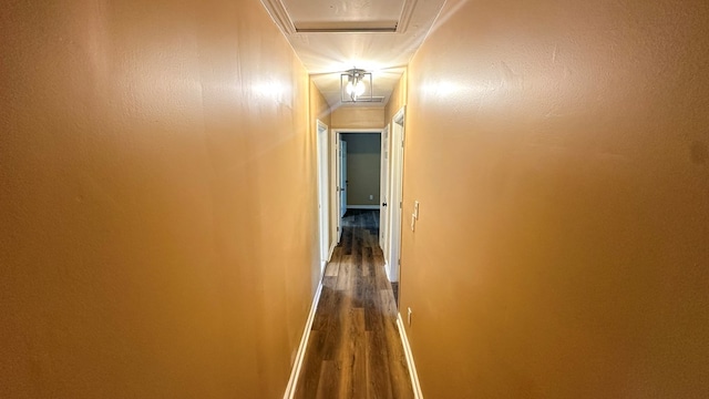 corridor with dark wood-type flooring, attic access, and baseboards