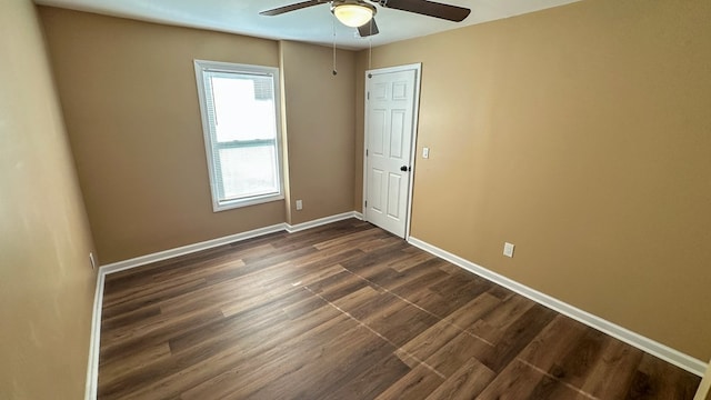 empty room with dark wood-type flooring, a ceiling fan, and baseboards