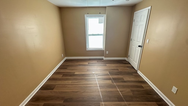 empty room with dark wood-style floors and baseboards