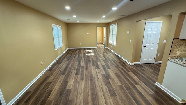 spare room featuring recessed lighting, dark wood finished floors, a wealth of natural light, and baseboards