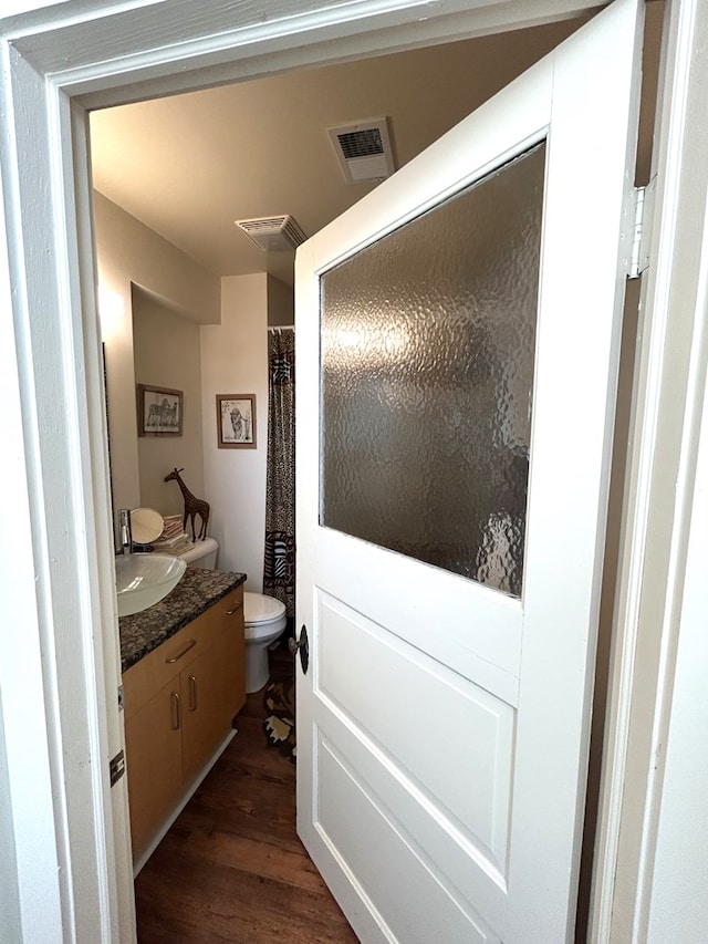 bathroom with hardwood / wood-style floors, vanity, and toilet