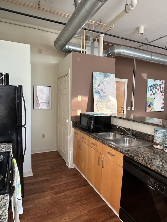 kitchen with sink, dark hardwood / wood-style floors, dark stone counters, and black appliances