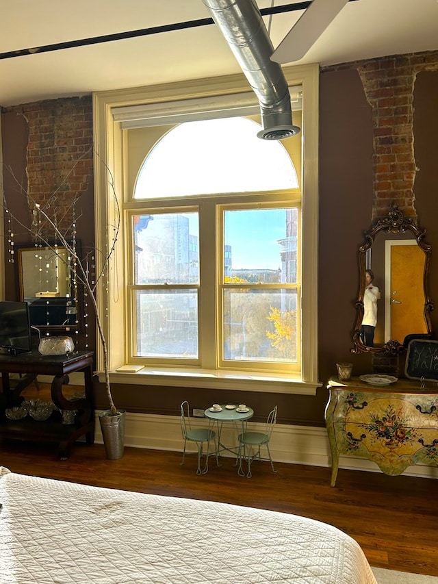 bedroom with hardwood / wood-style flooring and brick wall