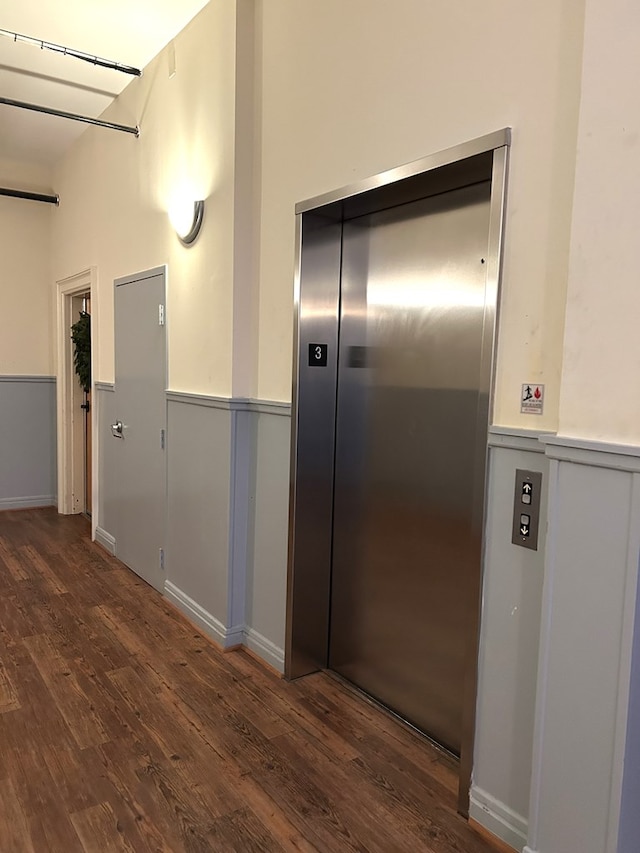 corridor with elevator and dark wood-type flooring