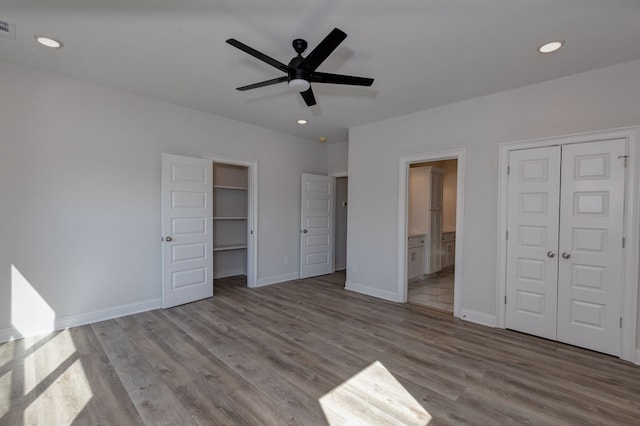 unfurnished bedroom with ceiling fan, ensuite bathroom, and light hardwood / wood-style flooring