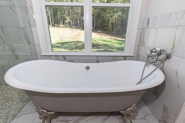 bathroom with a tub to relax in and tile walls