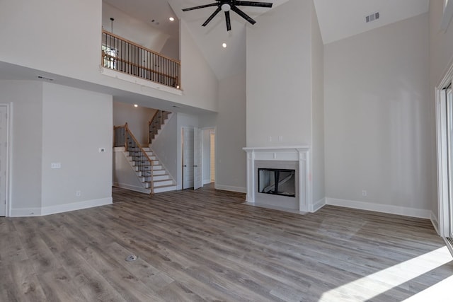 unfurnished living room featuring light wood-type flooring, high vaulted ceiling, and ceiling fan