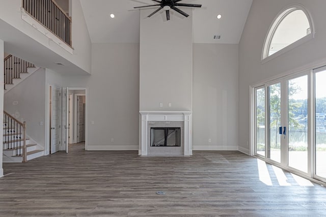 unfurnished living room featuring hardwood / wood-style flooring, ceiling fan, a fireplace, and high vaulted ceiling