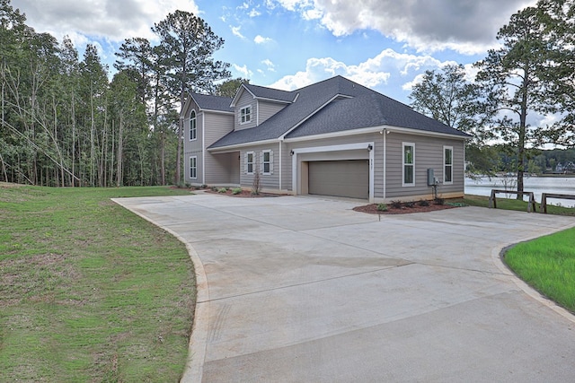 view of front of house with a front yard, a water view, and a garage