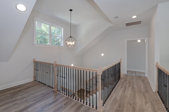 corridor with a notable chandelier and hardwood / wood-style flooring