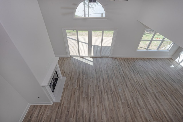 unfurnished living room featuring dark hardwood / wood-style floors, ceiling fan, and a towering ceiling