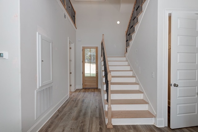 staircase featuring hardwood / wood-style floors and a high ceiling