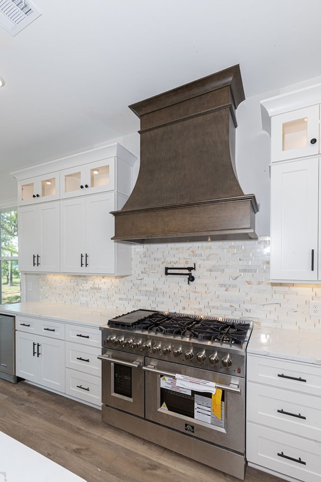 kitchen with dark hardwood / wood-style flooring, backsplash, double oven range, white cabinets, and custom exhaust hood