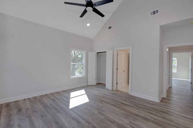 unfurnished bedroom featuring ceiling fan, high vaulted ceiling, and light wood-type flooring