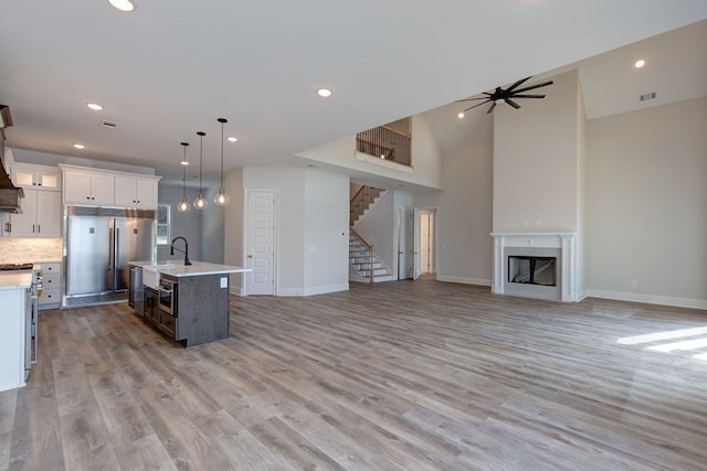 kitchen featuring ceiling fan, pendant lighting, white cabinets, light hardwood / wood-style floors, and an island with sink