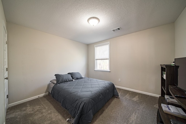 bedroom with a textured ceiling and dark colored carpet