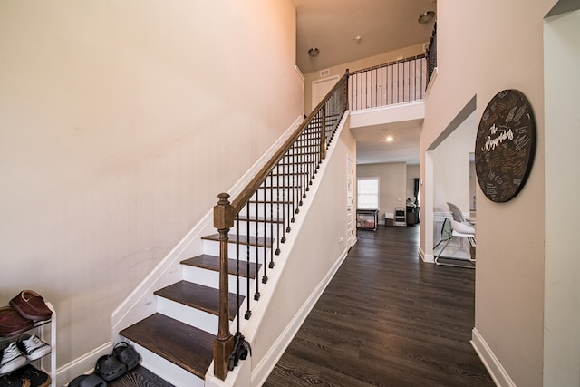 staircase featuring hardwood / wood-style floors and a towering ceiling