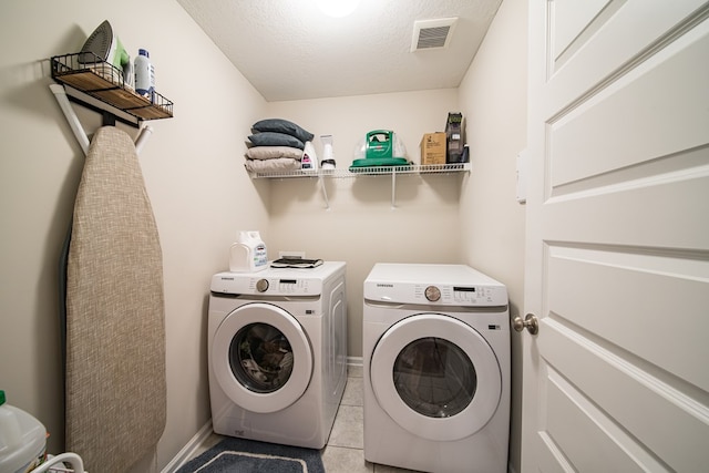 clothes washing area with light tile patterned floors, a textured ceiling, and washer and clothes dryer