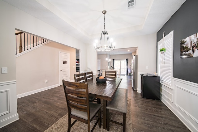 dining space featuring a raised ceiling, dark hardwood / wood-style flooring, and an inviting chandelier