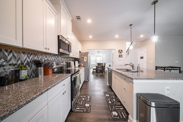 kitchen featuring sink, white cabinetry, stainless steel appliances, and an island with sink