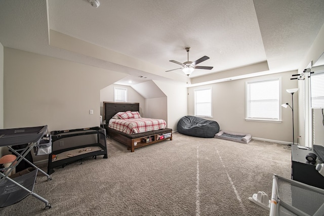 bedroom featuring a textured ceiling, carpet floors, a raised ceiling, and ceiling fan