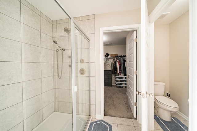 bathroom featuring tile patterned flooring, a shower with door, and toilet