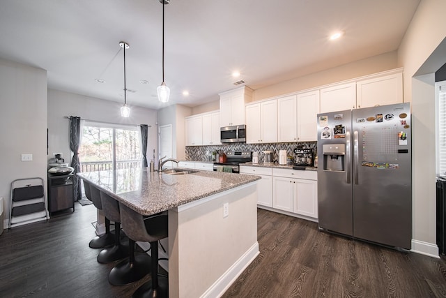 kitchen featuring a kitchen island with sink, white cabinets, hanging light fixtures, and appliances with stainless steel finishes