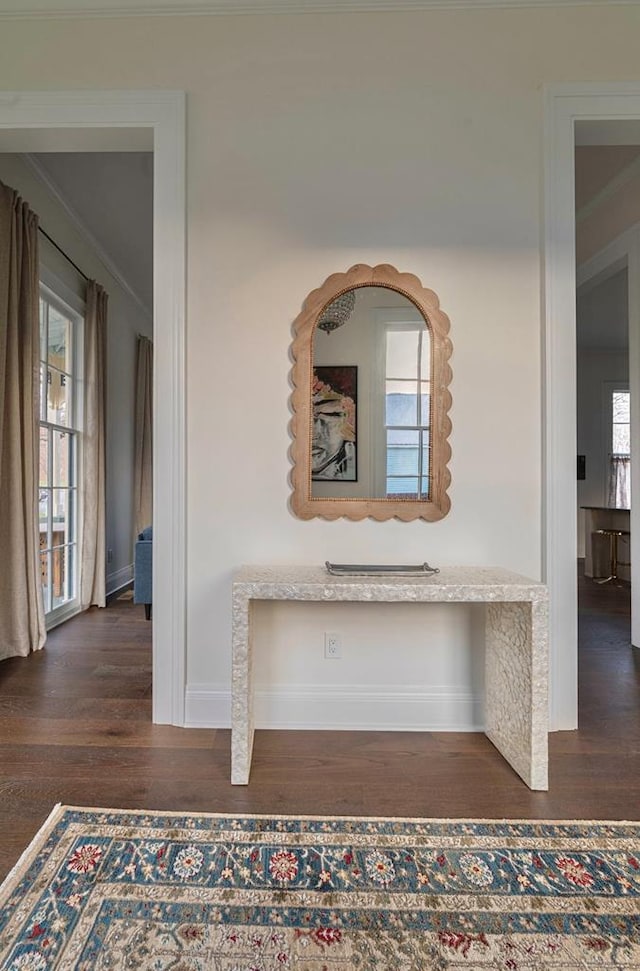 hallway with dark wood-style floors, baseboards, and crown molding