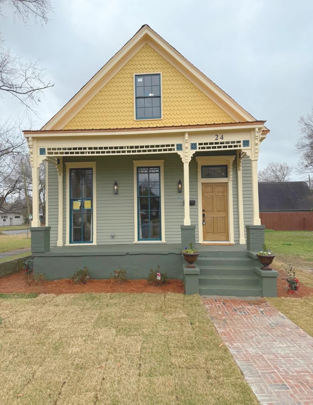 victorian house featuring covered porch and a front yard