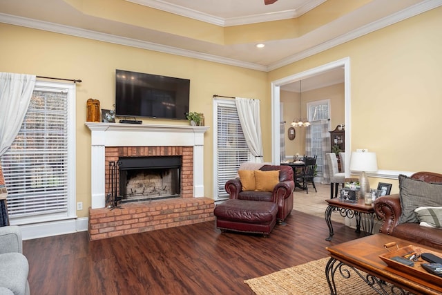 living room featuring hardwood / wood-style flooring, a fireplace, ornamental molding, and a raised ceiling