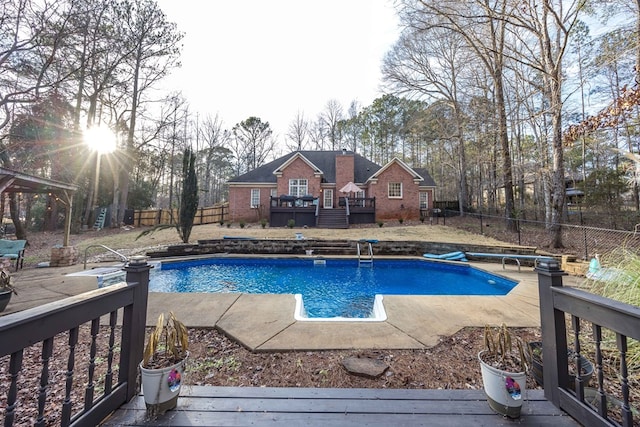 view of pool with a wooden deck and a diving board