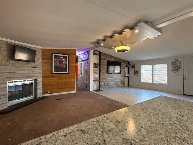 unfurnished living room featuring wooden walls, a large fireplace, carpet flooring, visible vents, and vaulted ceiling