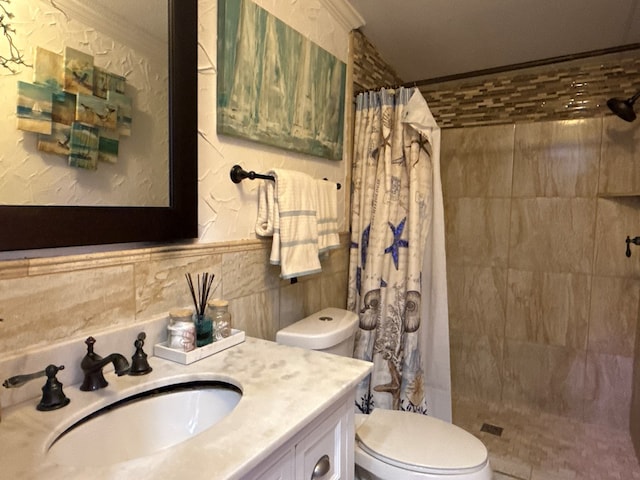 bathroom with tiled shower, vanity, toilet, and tile walls